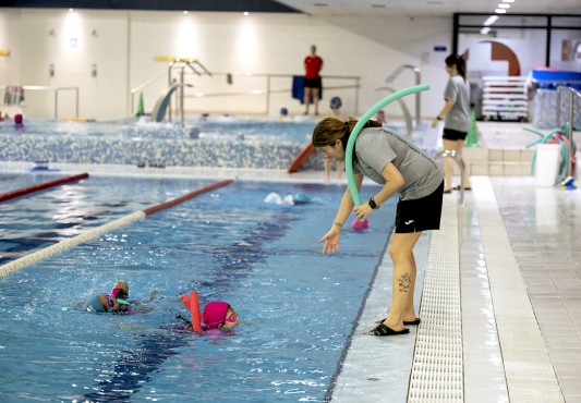 La imagen muestra un curso de natación en la piscina