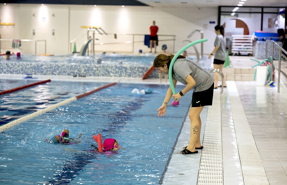 La imagen muestra un curso de natación en la piscina